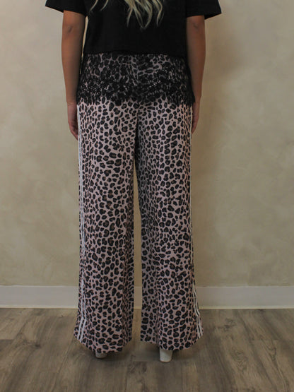 Back view of a woman model wearing a pair of leopard print pants.