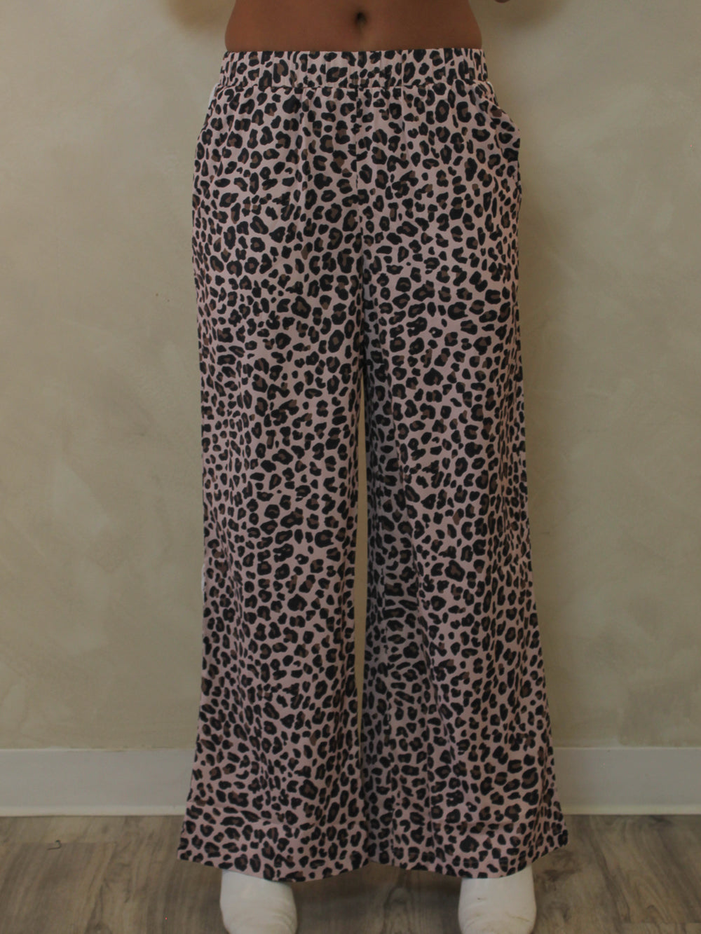 A woman modeling a pair of leopard wide leg pants.
