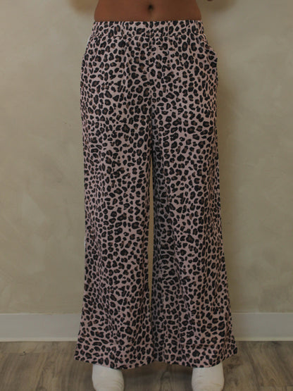 A woman modeling a pair of leopard wide leg pants.