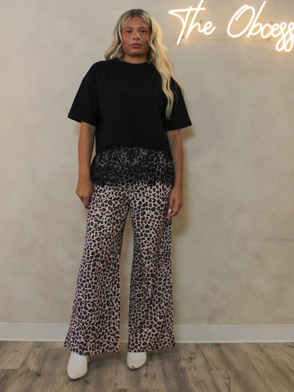 A woman wearing leopard pants outfit styled with a black lace t-shirt.