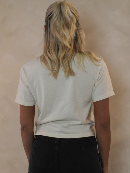 Woman wearing an off white cropped tee from the back