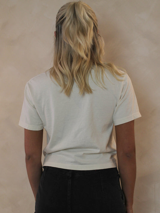 Woman wearing an off white cropped tee from the back
