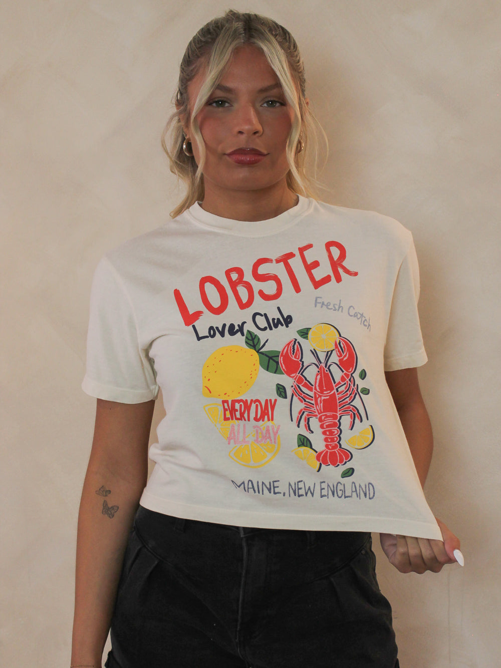 Woman wearing a cropped white tee with Lobsters on the front