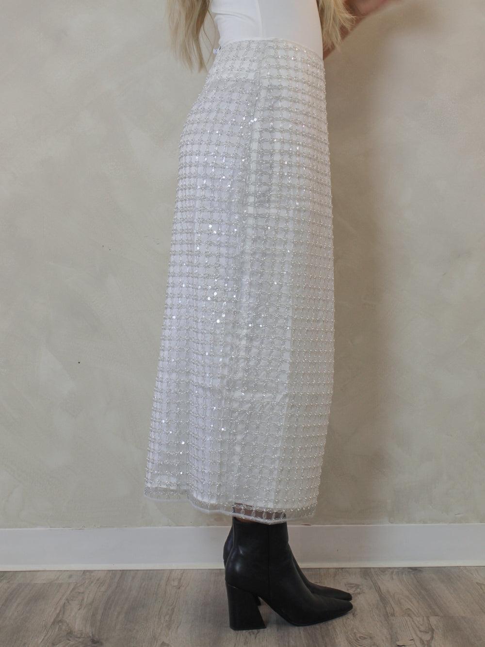 Woman wearing a sparkling sequin white skirt with black ankle boots 