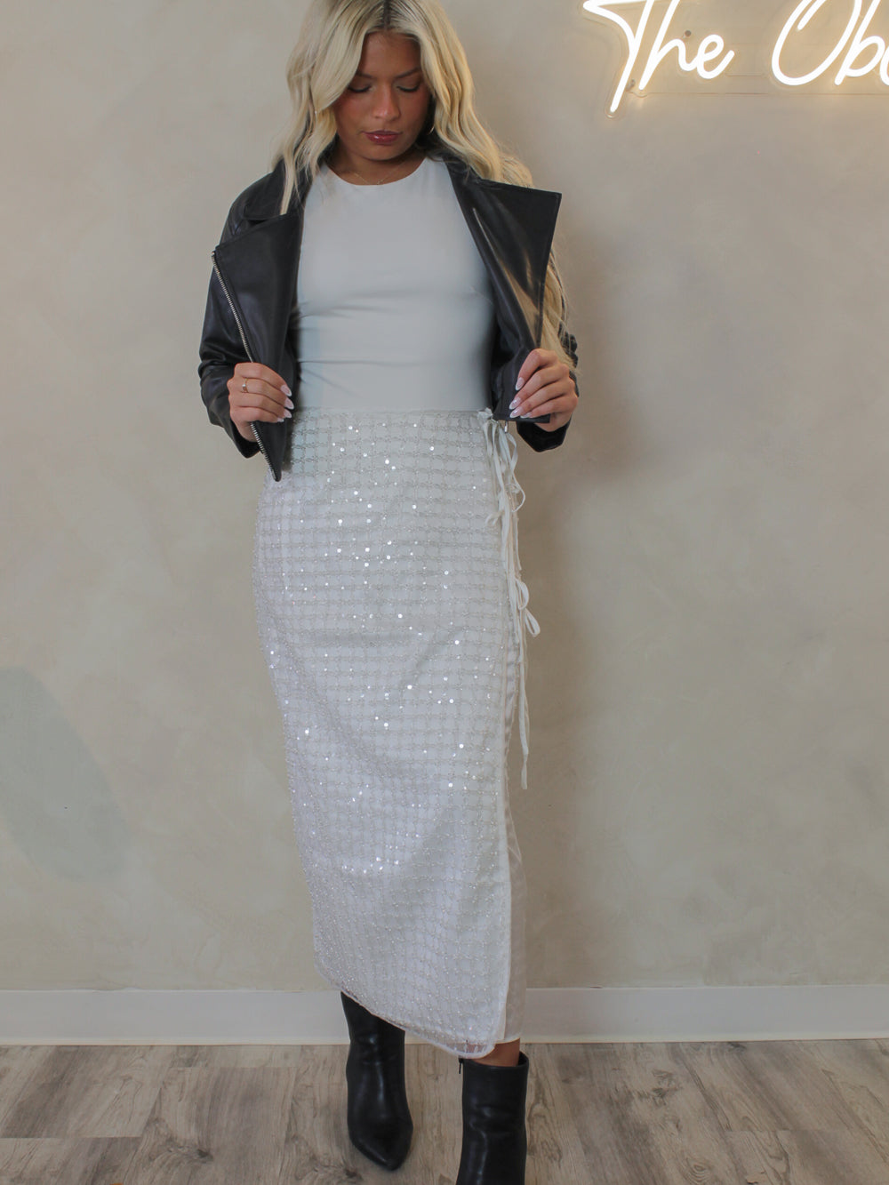 Woman wearing a white sequin skirt for the holiday and black leather jacket 