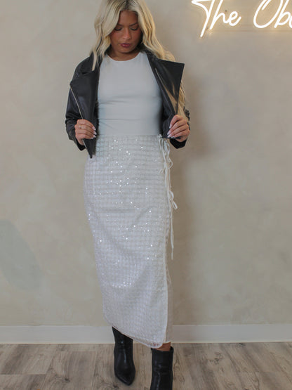 Woman wearing a white sequin skirt for the holiday and black leather jacket 