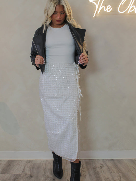 Woman wearing a white sequin skirt for the holiday and black leather jacket 