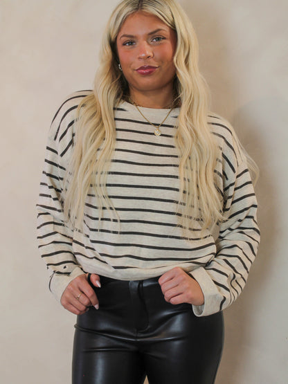 Woman wearing a cream sweater with grey stripes 