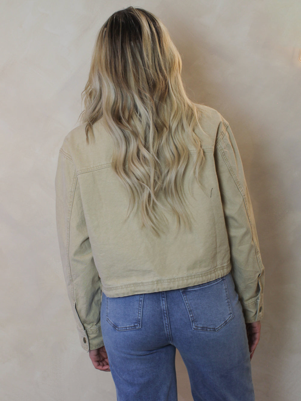 Woman wearing a tan, twill barn style jacket 