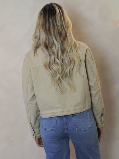 Woman wearing a tan, twill barn style jacket 