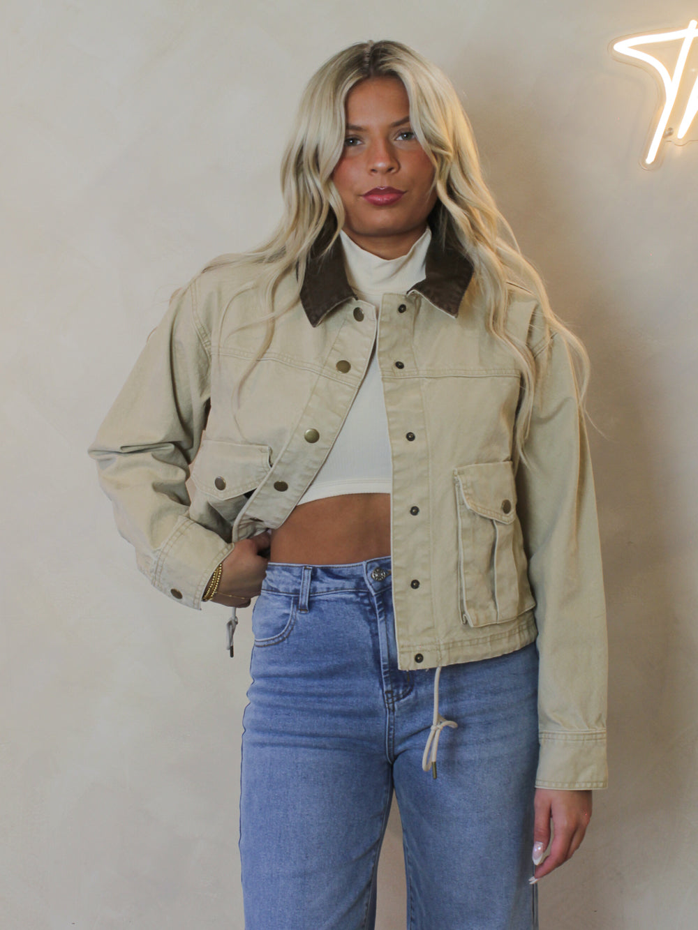 Woman wearing a tan barn style jacket with a brown collar