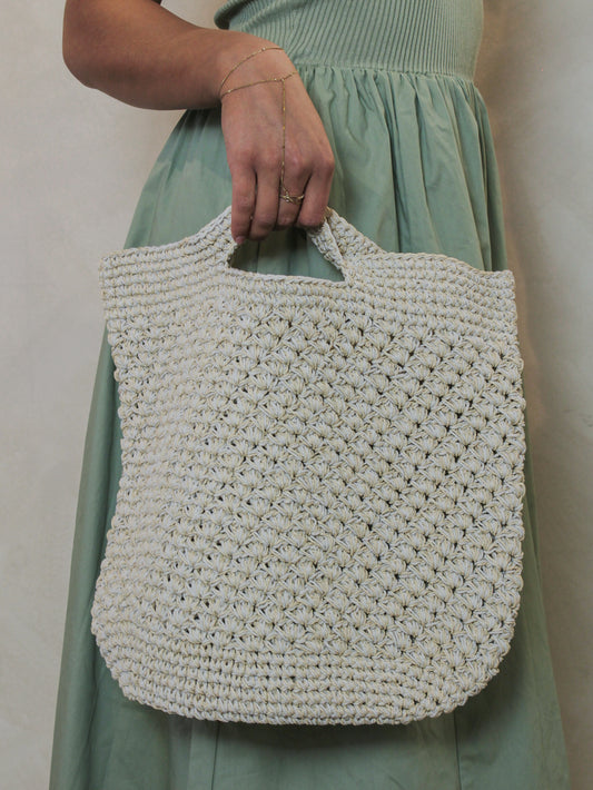 Woman holding a beige woven tote bag for summer