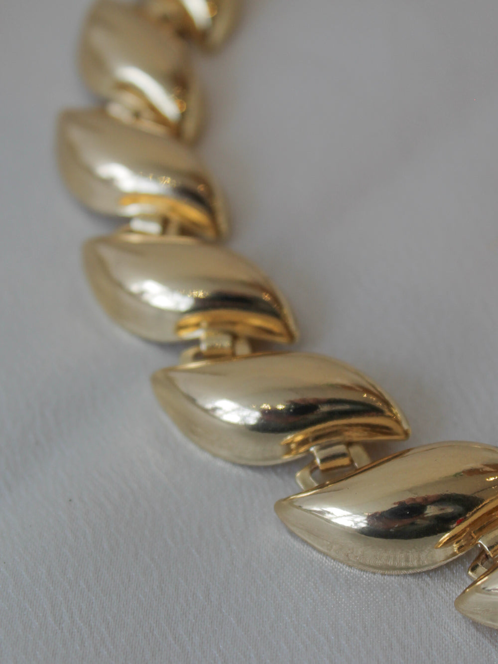Close up of a gold statement bracelet with curved links 