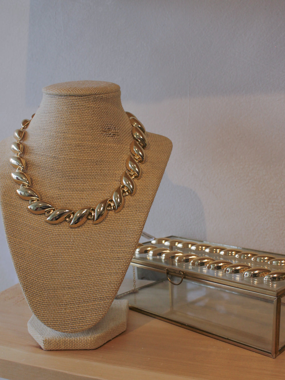 Gold necklace on a mannequin bust with matching bracelet 