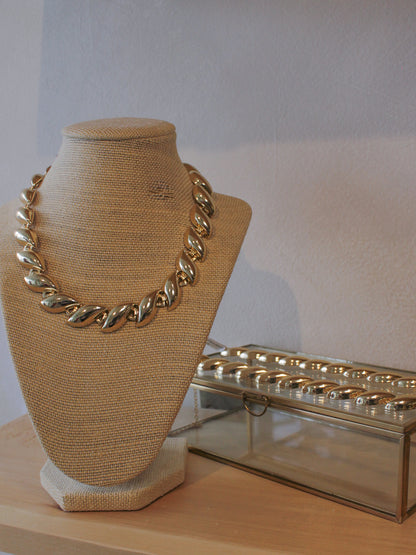 Gold necklace on a mannequin bust with matching bracelet 