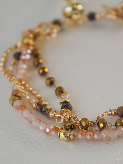 Close-up of a beaded bracelet with gold, neutral and pink beads 