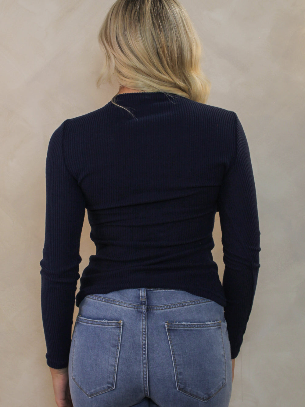 Model wearing a navy ribbed sweater for fall transition with medium wash denim