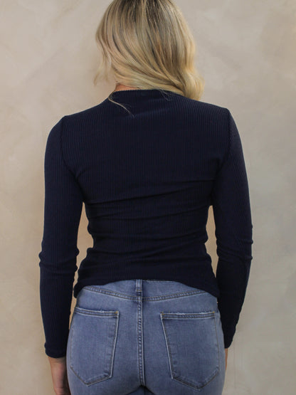 Model wearing a navy ribbed sweater for fall transition with medium wash denim