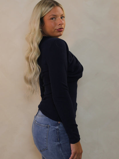 Model wearing a dark blue ribbed sweater with jeans for fall.