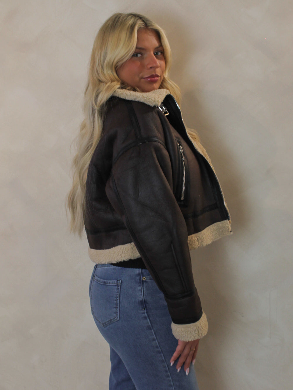 Side view of the Olivaceous brown leather jacket with faux fur details 