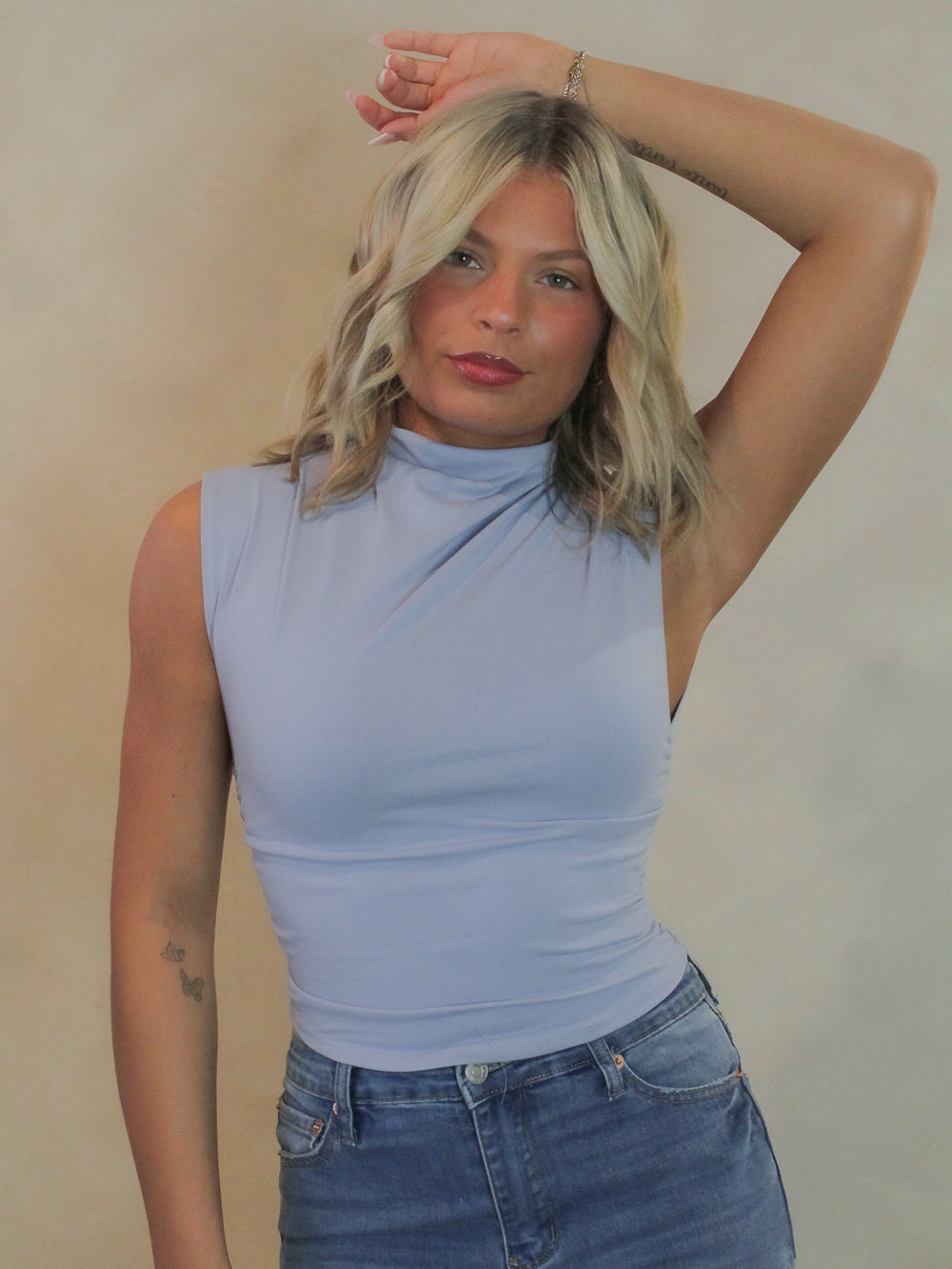 Women wearing a soft blue sleeveless top with ruched sides.