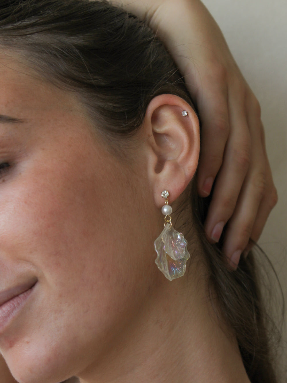 Close-up of a woman wearing iridescent shell earrings for summer.