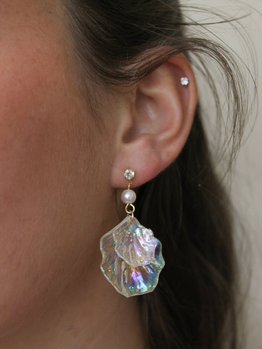 Close-up of an ear wearing a pearl and iridescent crystal earring.