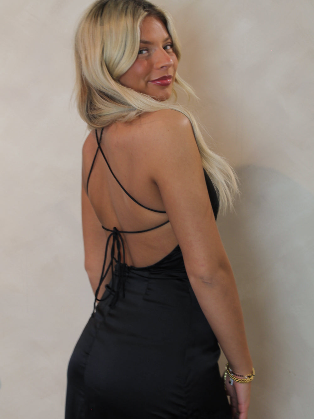 Model wearing a black strappy backless dress