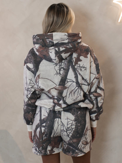 Model wearing a camouflage hoodie and shorts set