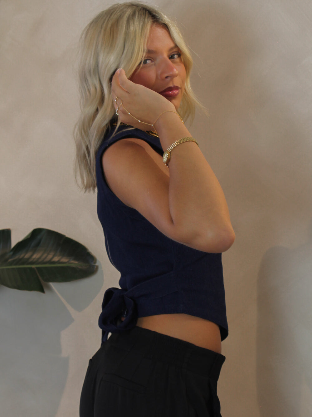 woman wearing a dark denim top with a pointed hem and tie back detail