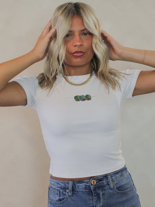 Woman wearing a white tee with a beaded olive graphic 