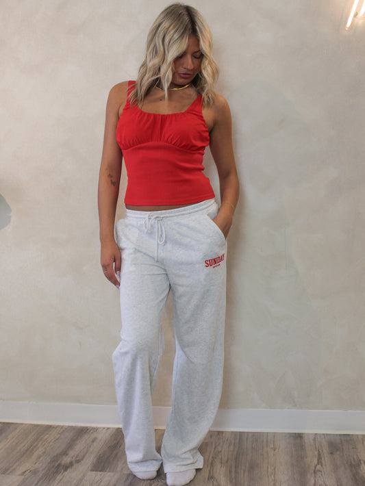 Woman wearing a red tank top and grey sweatpants with 'Sunday Coffee Club' text 