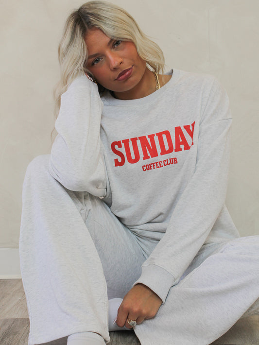 Person wearing a gray sweatshirt with 'SUNDAY COFFEE CLUB' text,