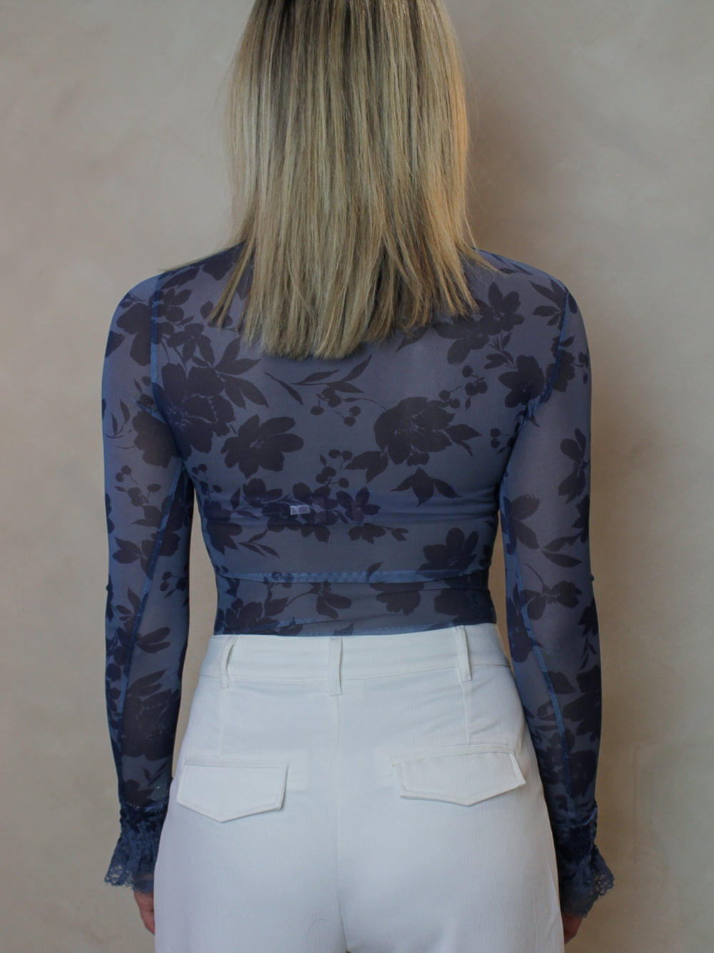 back view of a blue, floral mesh bodysuit.