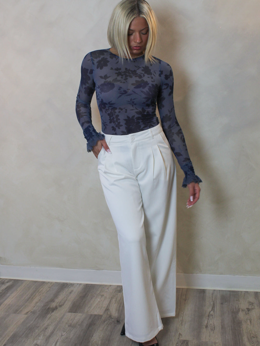 a blue, long sleeve, mesh bodysuit with white trousers outfit.