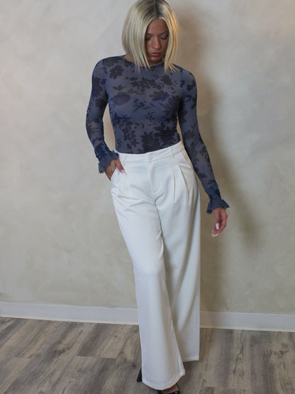 a blue, long sleeve, mesh bodysuit with white trousers outfit.