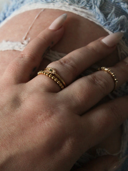 She is wearing an evil eye and gold beaded ring 