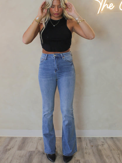 Model wearing a pair of high waist flared denim in a medium wash 