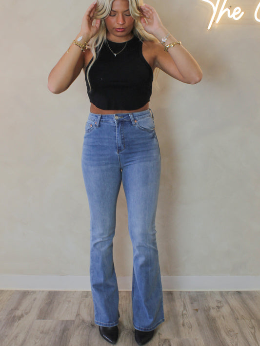 Model wearing a pair of high waist flared denim in a medium wash 