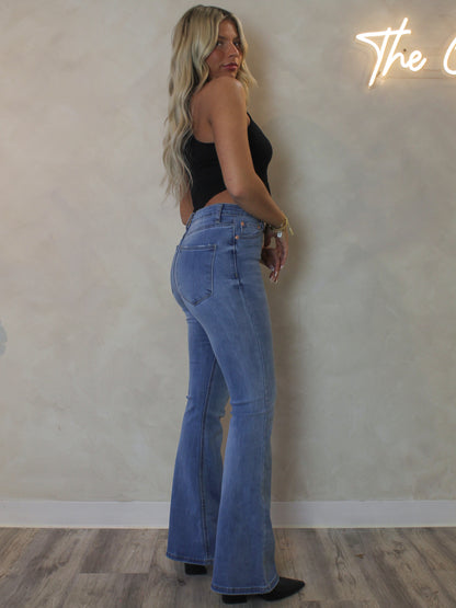 Woman wearing a pair of medium wash flare denim 