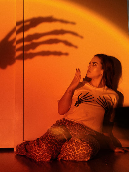 Woman wearing a skeleton hand shirt with a skeleton hand background 
