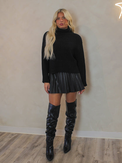 Woman wearing an all black outfit for winter featuring a black turtle neck sweater