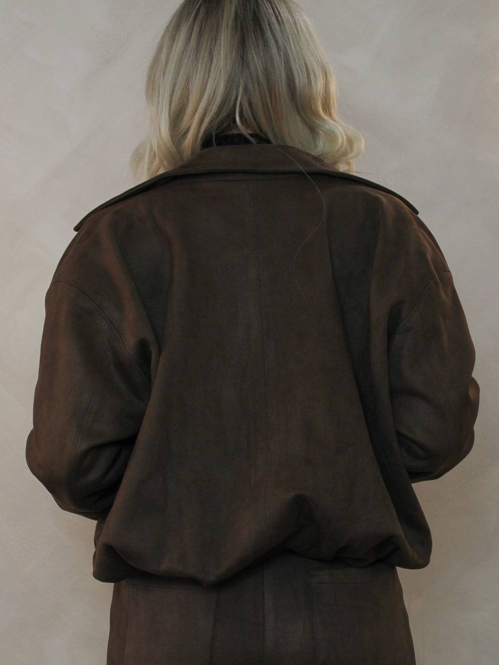 Woman wearing dark brown leather jacket showing the back view