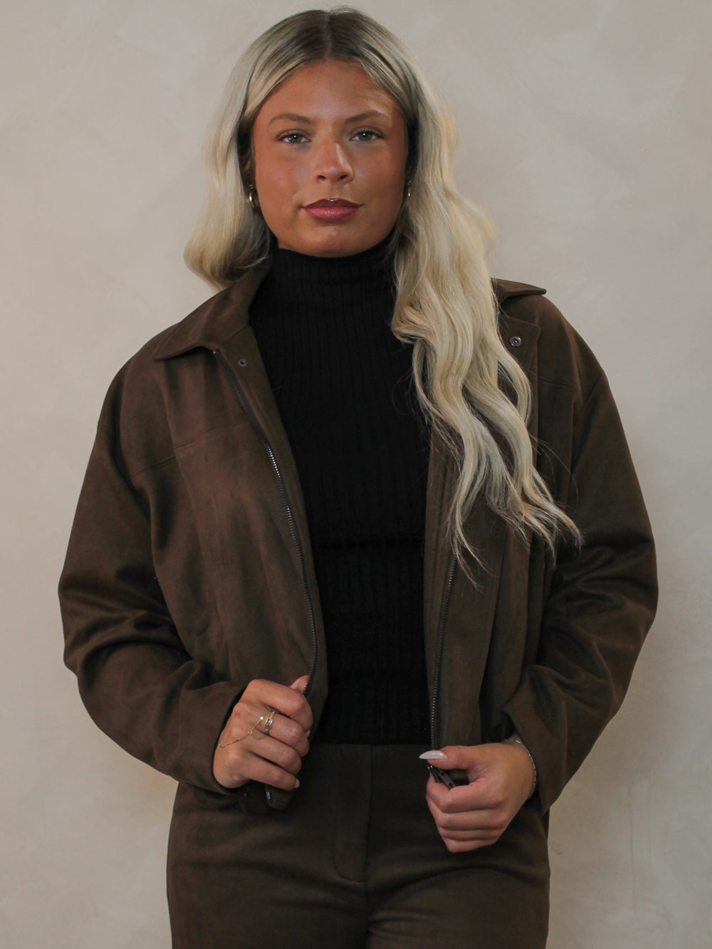 Woman wearing a chocolate brown faux suede jacket with matching pants for fall