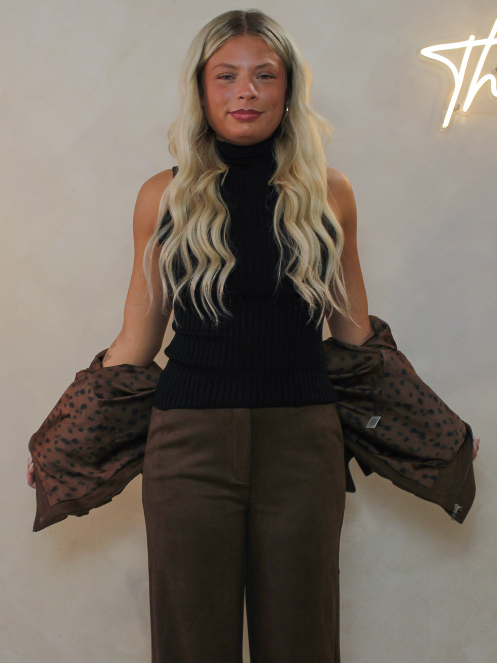 Woman wearing a brown faux suede set for fall showing off the inner lining of the jacket
