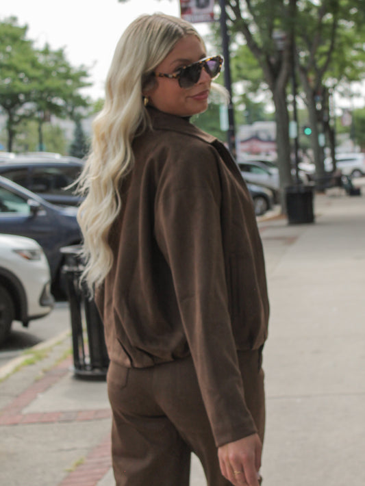 Girl wearing a brown faux suede jacket with matching pants, walking down the street