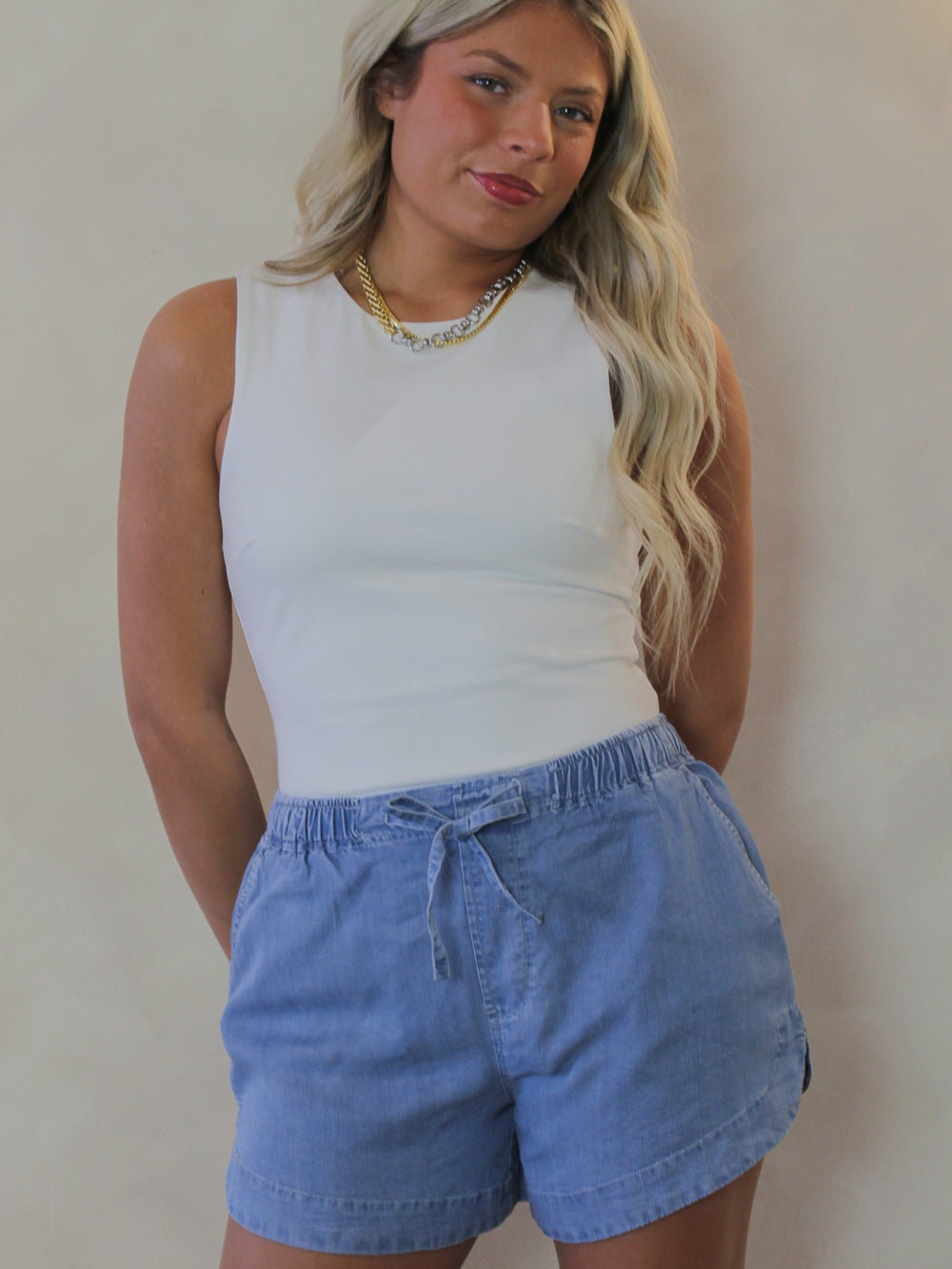 Woman wearing a white tank and light denim tencel shorts