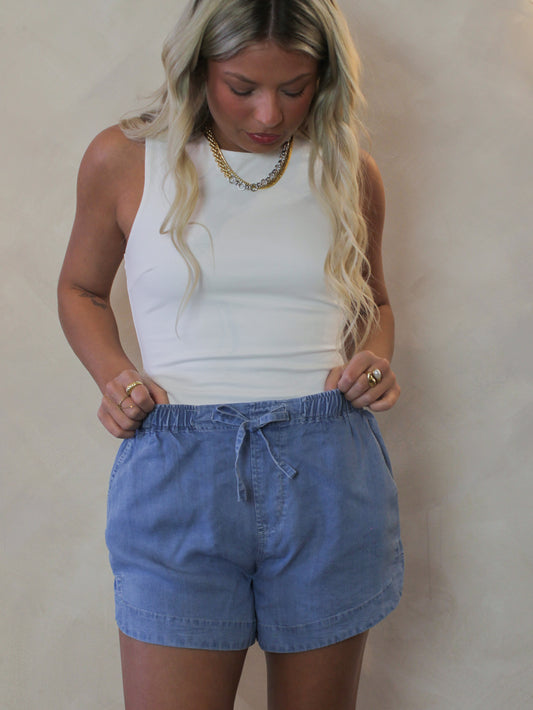 Model wearing a pair of tencel denim shorts and white tank 