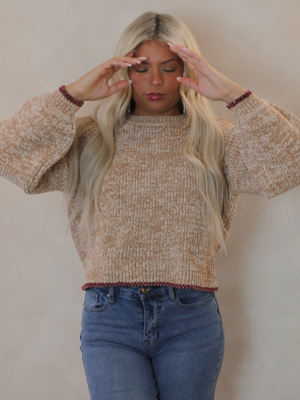 Woman wearing a beige sweater with red contrast hems