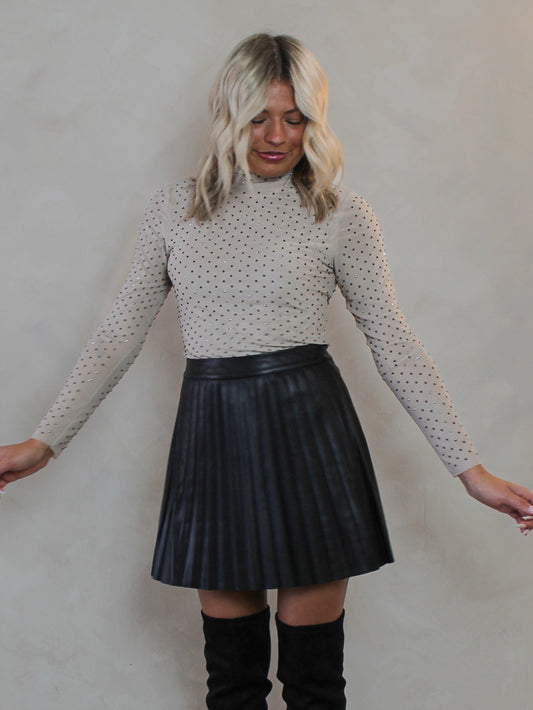Woman wearing a light beige mesh top with silver sparkle embellishments 
